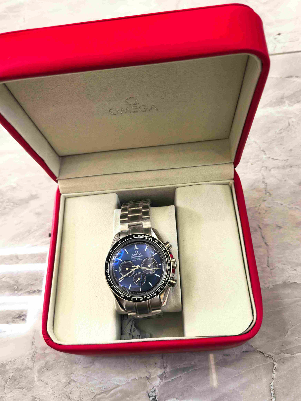 Omega Speedmaster chronograph watch with gold-tone case and green strap
