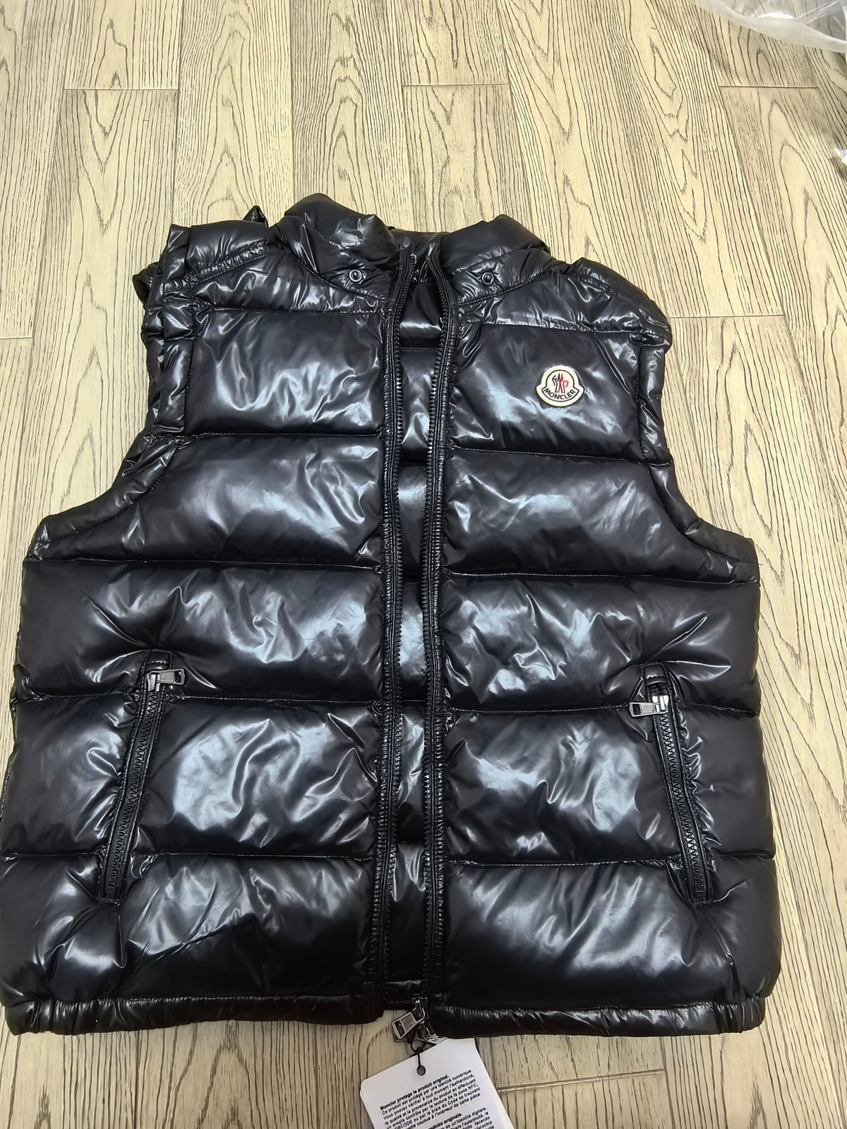 Black glossy puffer vest front with zippered pockets