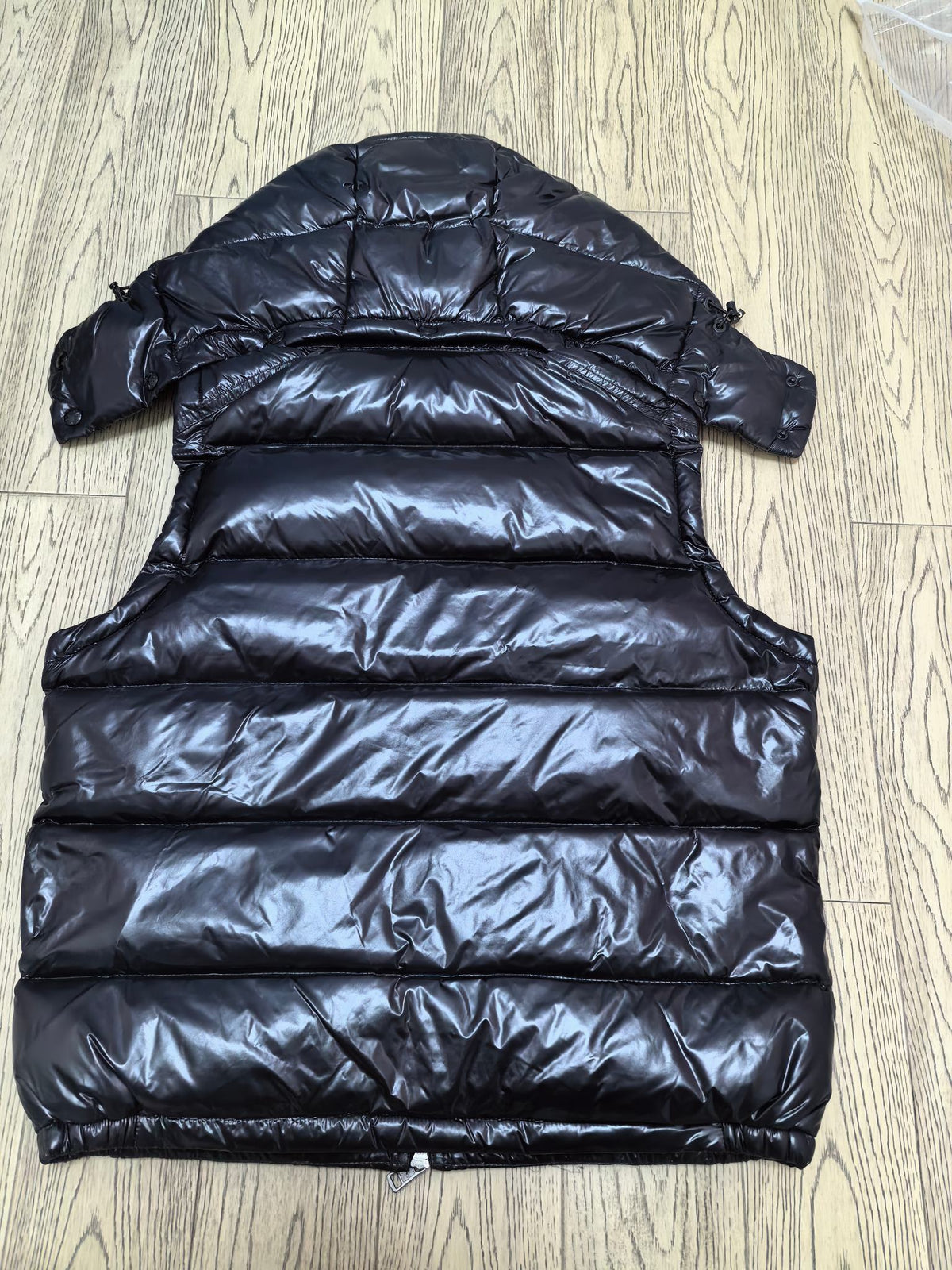 Back view of black glossy hooded puffer vest