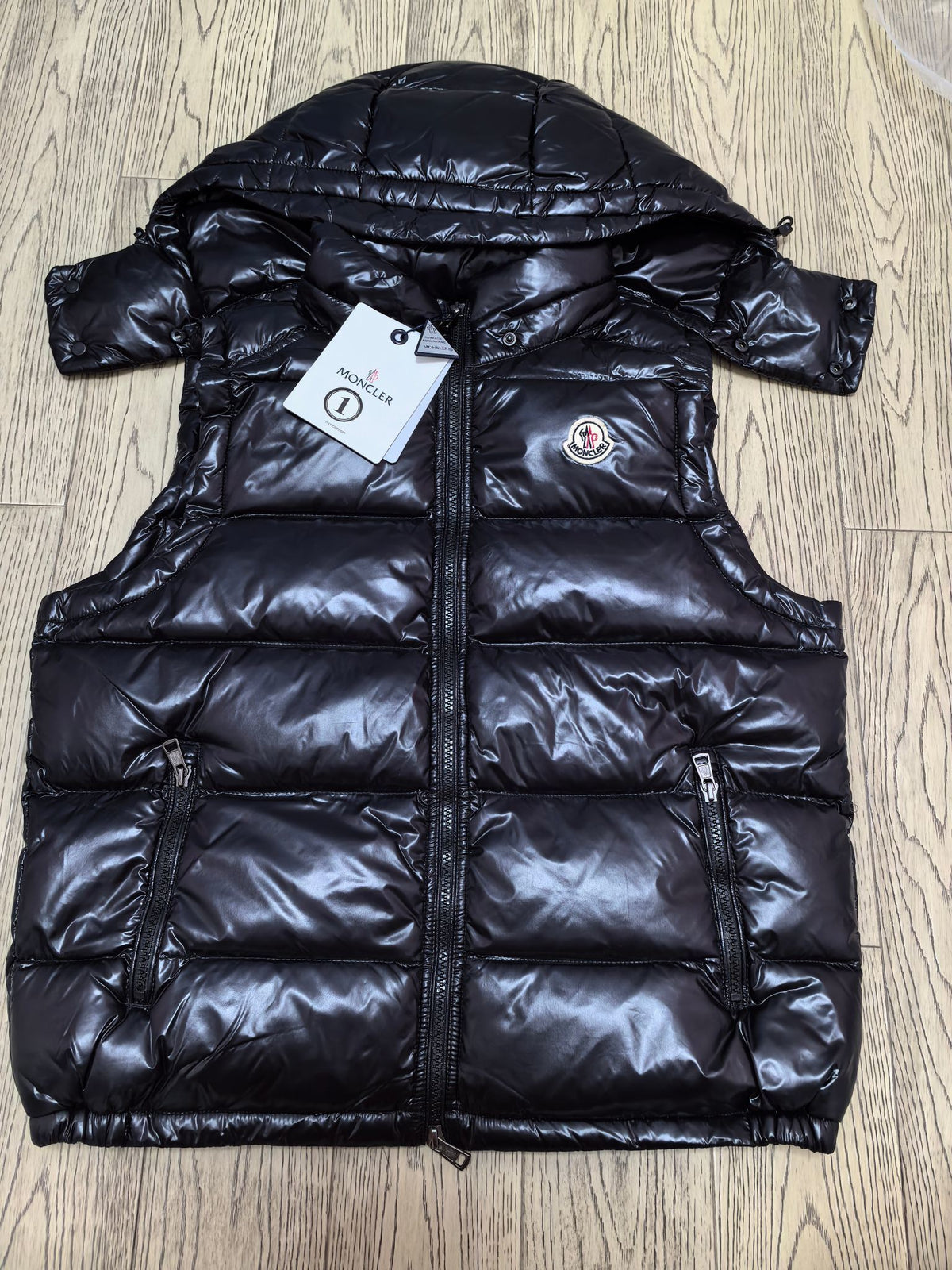 Black quilted puffer vest front view with hood and tags