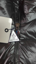 Black glossy hooded puffer vest hanging, front view